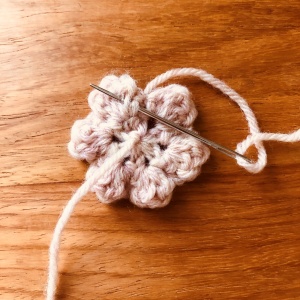 かぎ針編みの花のモチーフ、とじ針で糸を処理している