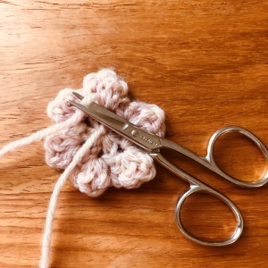 かぎ針編みの花のモチーフ、糸処理が終わりはさみで糸を切る